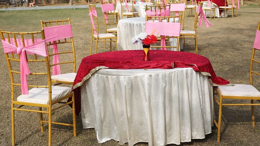 Outdoor table setup with pink-decorated chairs on a lawn at Tisya Farms, Gurgaon.