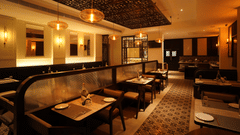 Restaurant dining area at V FIVE HOTEL with tables, chairs, plates, glasses, water bottles, pendant lights, wall mirrors, patterned floor tiles, and a buffet counter in the background.