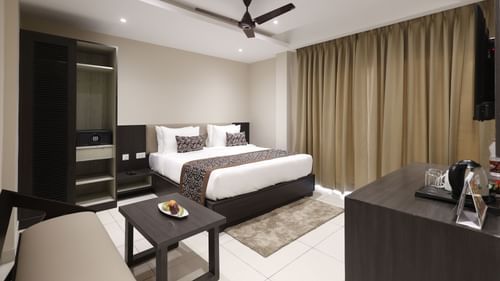 Premium Room at Pride Biznotel Canopus, Digha featuring a plush bed in front of a TV mounted on the wall and a sitting space with a couch and a coffee table