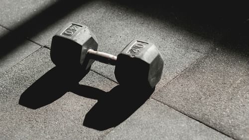 A dumbbell with the weight of it inscribed on it placed on a workout mat