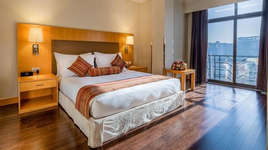 A well-lit, luxurious hotel room with a king-size bed, side tables and lamps at Ramada by Wyndham Addis, Addis Ababa.