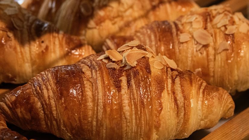 Freshly baked croissants stacked in a basket, topped with almond flakes and crisp layers.
