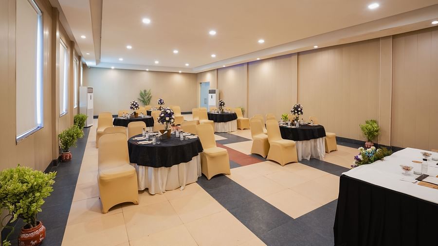 Well-lit meeting area with tables set with a flower bouquet at Shri Radha Brij Vasundhara Resort & Spa, Mathura
