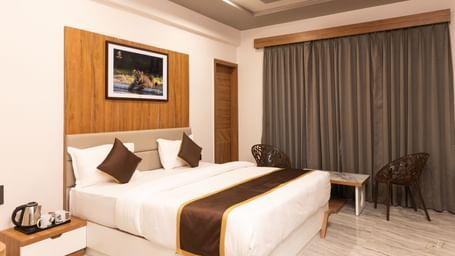Highlighting the double bed situated in the centre of the Daksh Comfort Room at Daksh Eden Greenz, Sasan Gir.