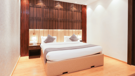 Comfortable king size bed with elegant wood paneLling and ambient lighting in a premium room at Hyphen Premier Hotel, Meerut.