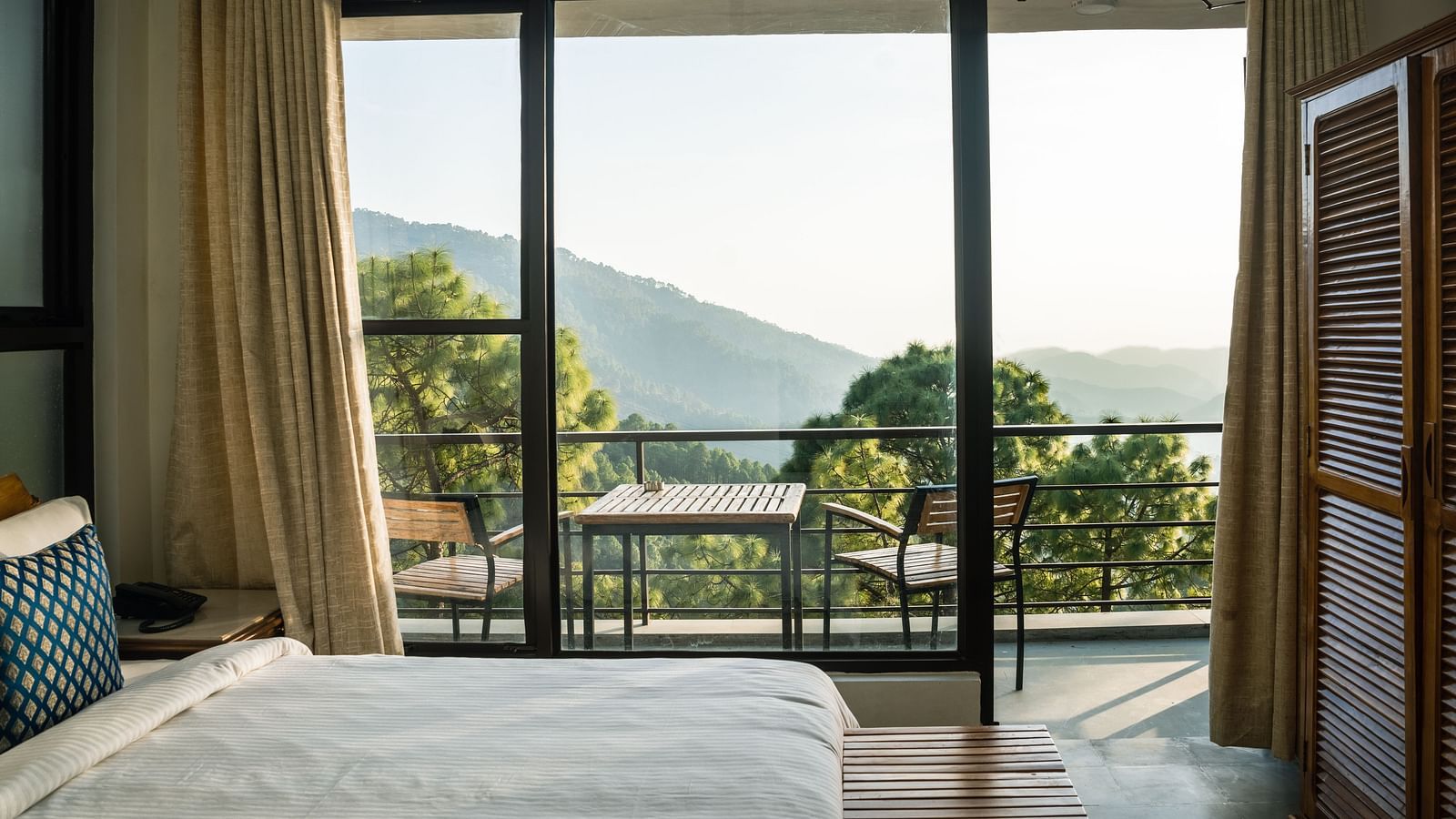 A bedroom with a balcony offering natural light and scenic views at BluSalzz Escapade Resort, Lansdowne