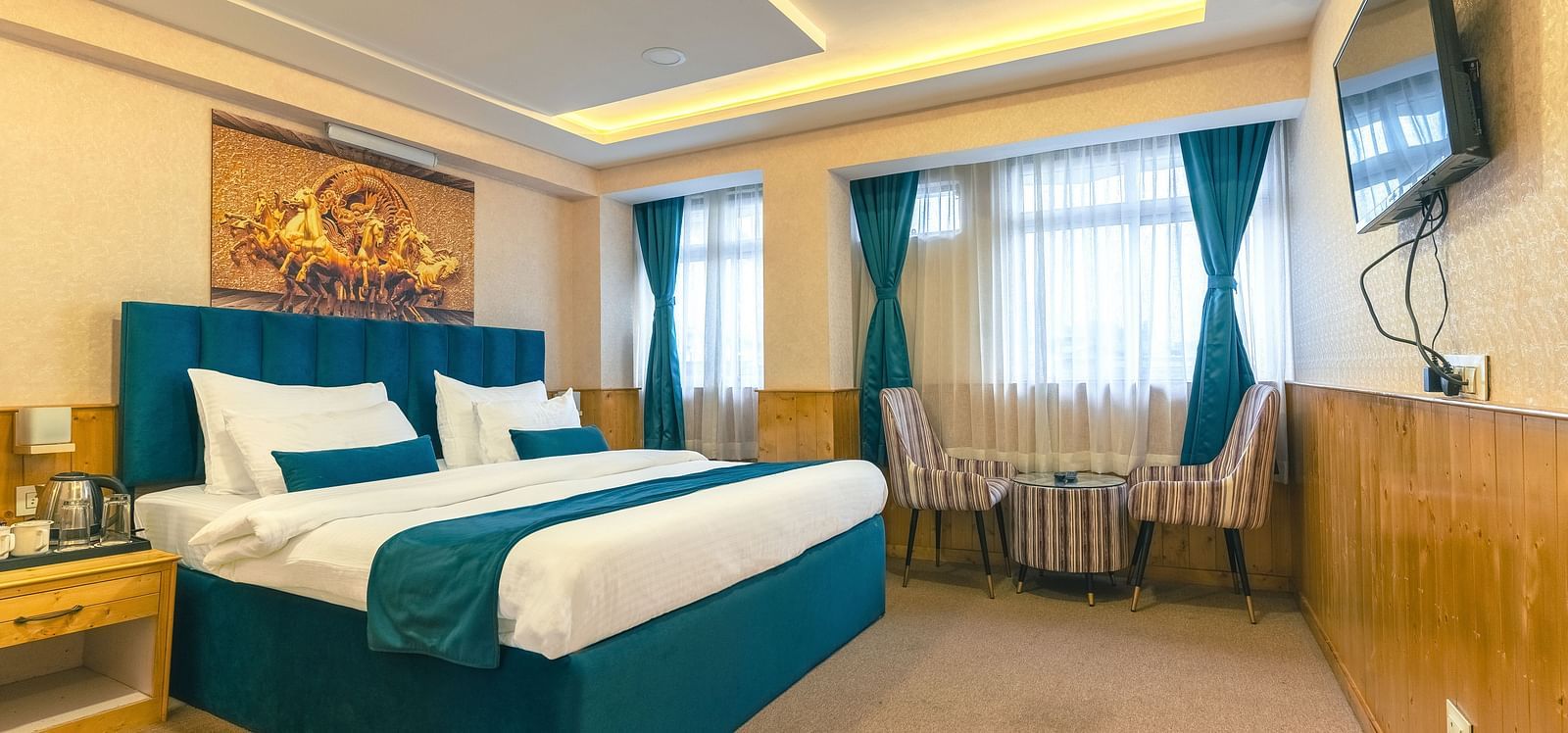 Deluxe Room Avianna Seven Seas, Deluxe Room with a king size bed, inviting ambiance, wooden bedside table, and a large window with curtains drawn along with a wall mounted television at Avianna Seven Seas, Darjeeling.