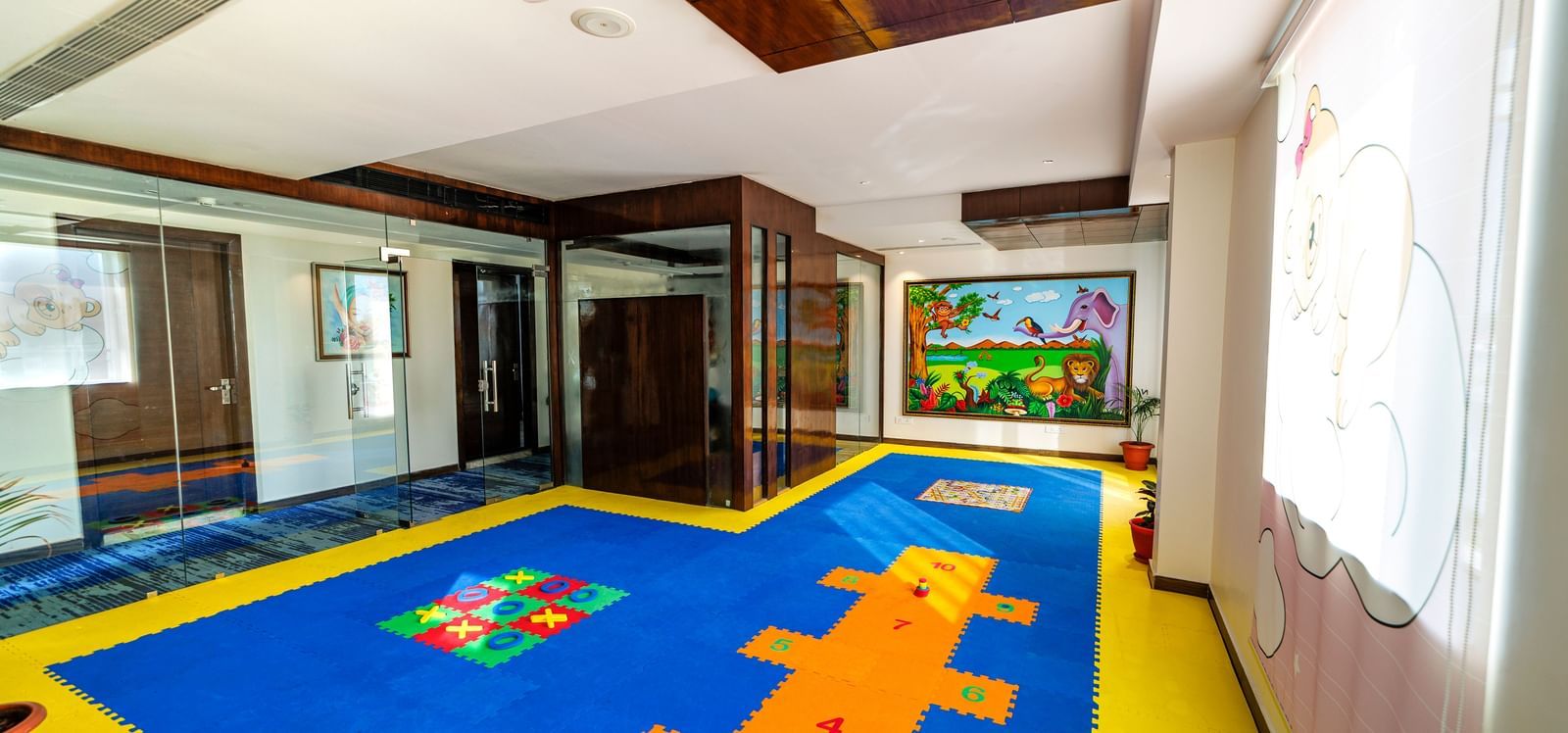 Children's playroom at Inde Reva Resorts Rishhikesh with colourful flooring, soft blocks, indoor lighting, and wall mural.