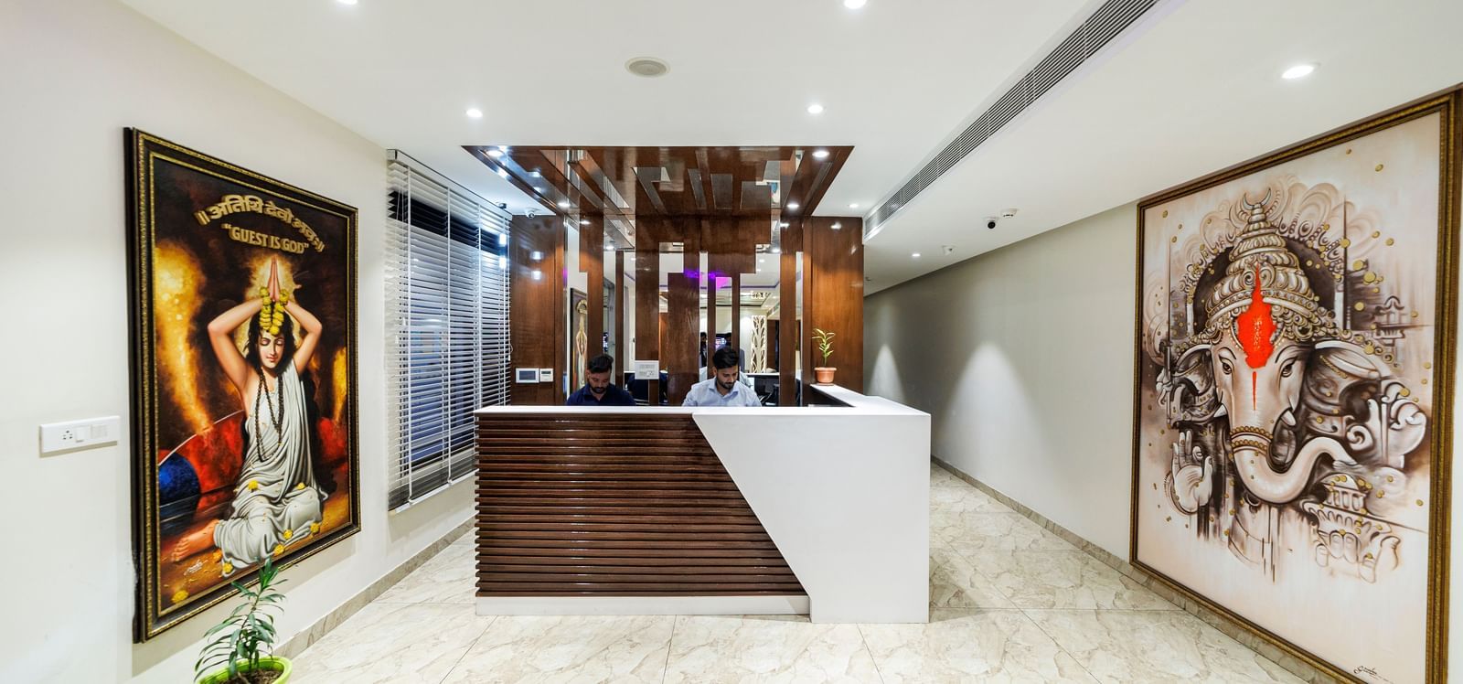 Reception area at Inde Reva Resorts Rishhikesh with front desk, ceiling lights, and wall art on both sides.
