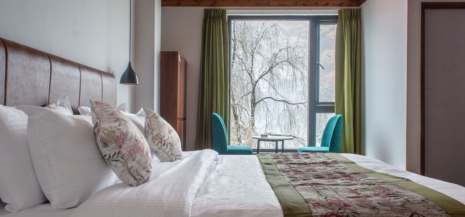 view of the room with a large bed and a balcony view in the background at Mystique Valley Resort  