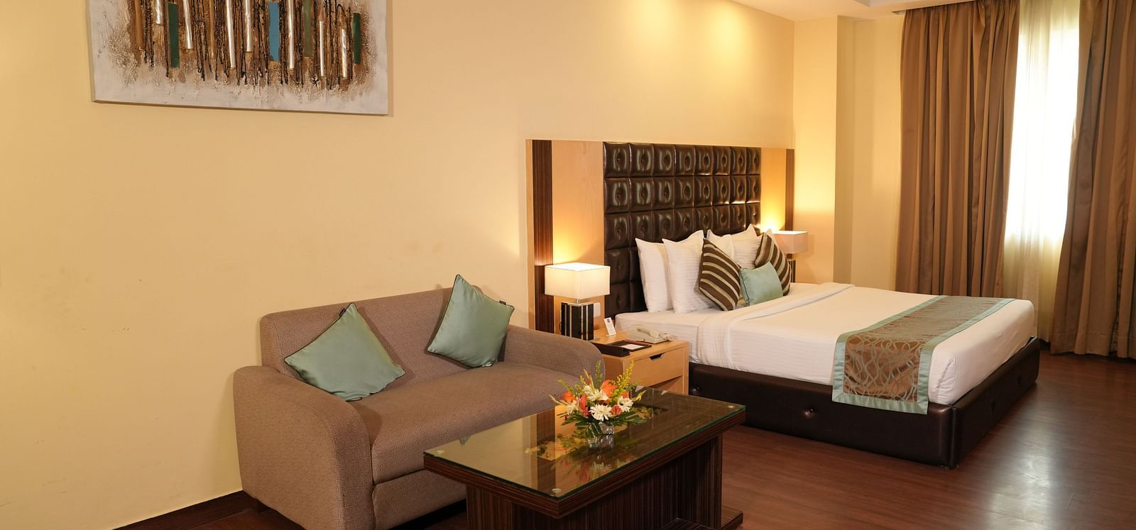 Spacious hotel room with a bed, seating area, and large window - Grand Plaza Lords Inn Jammu