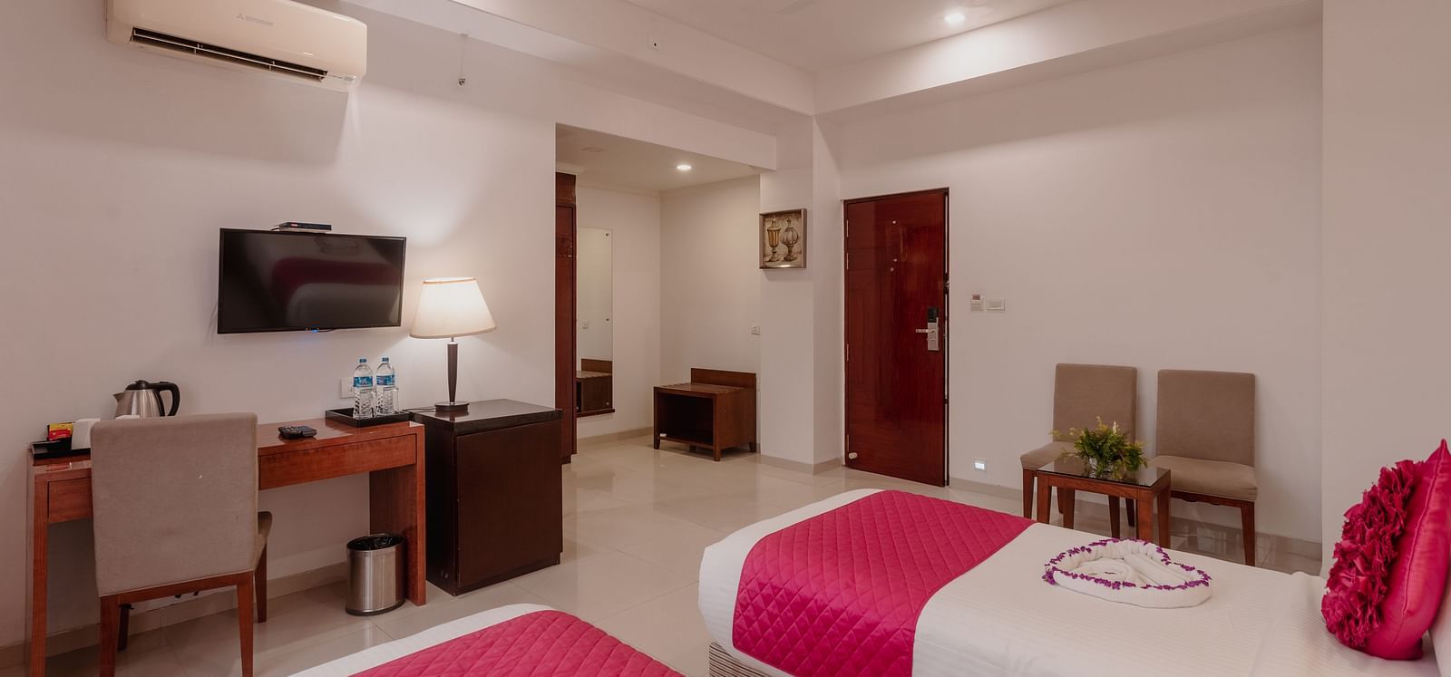 Twin room at Diamond Palace Lords Plaza with two single beds featuring pink accents, a work desk, and a mounted TV.