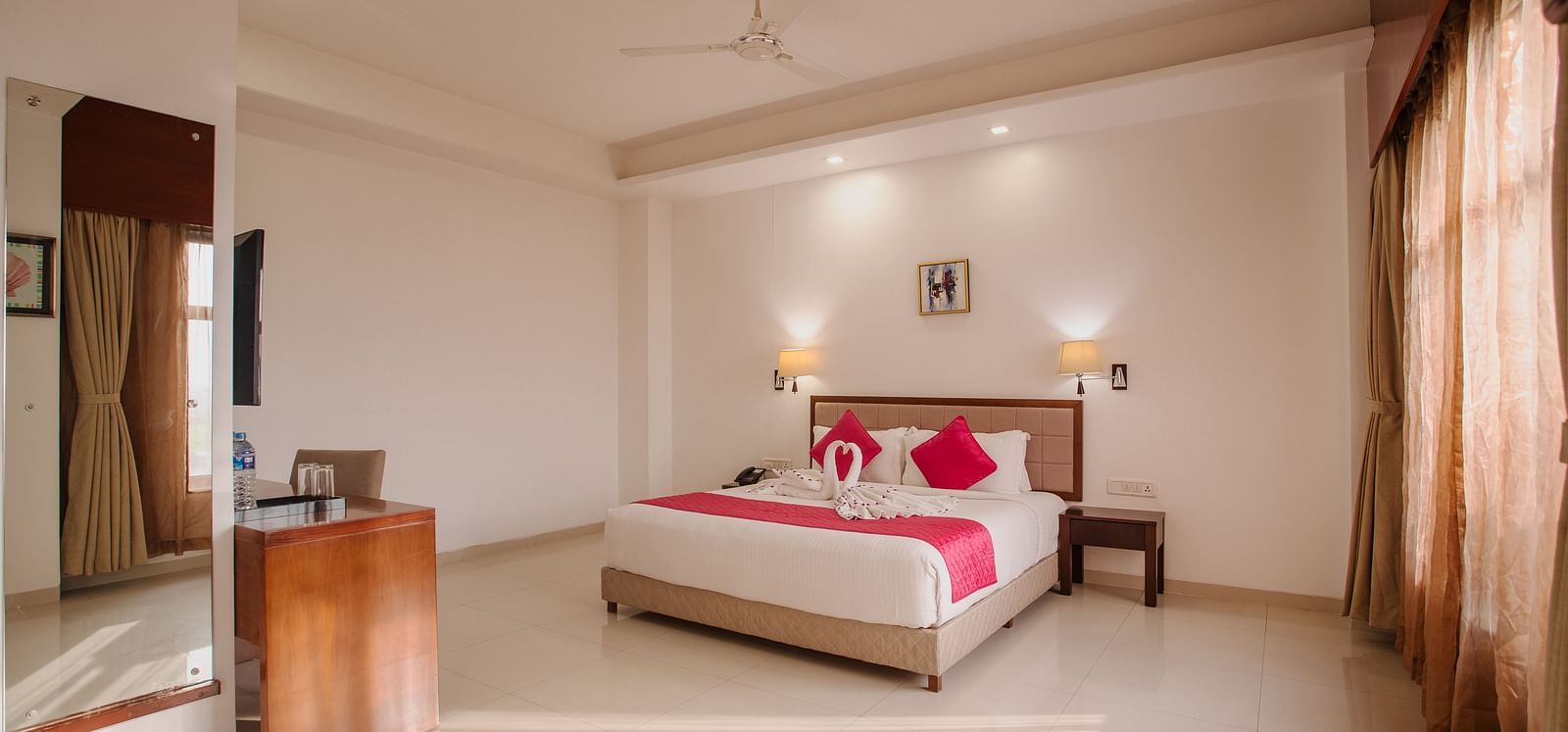 Airy hotel room at Diamond Palace Lords Plaza featuring a double bed with bright accents and natural light from a window.