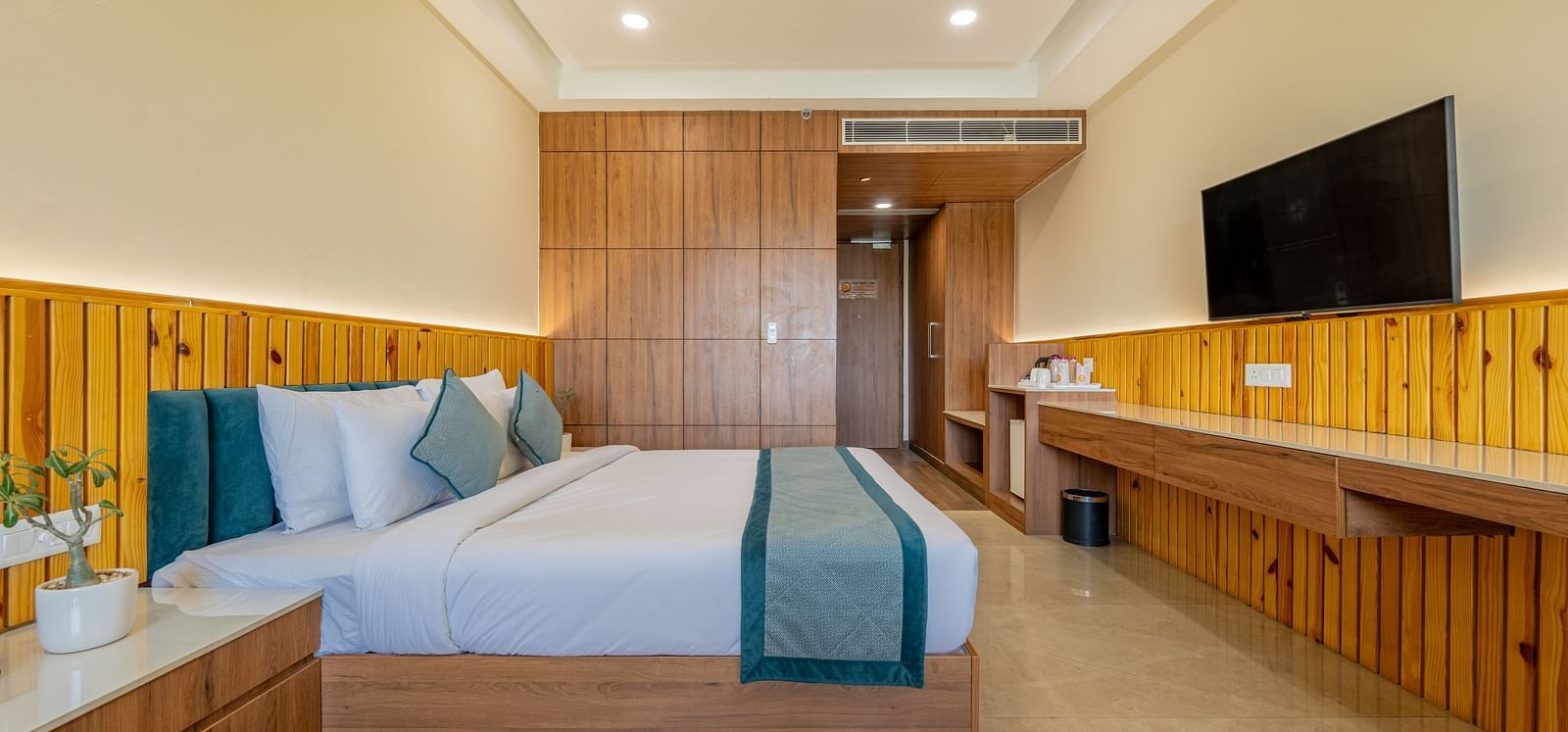 Modern room with king bed, flat-screen TV, and wooden decor accents in an executive king room at Hotel Highway, Bagru.