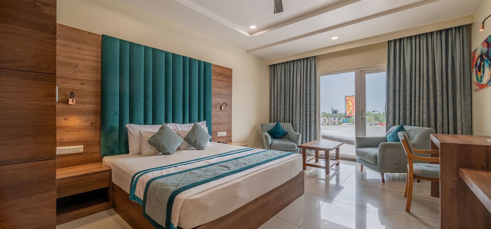 Elegant room with king size bed, full-length curtains, and work station with a seating area nearby at Hotel Highway King, Bilaspur.