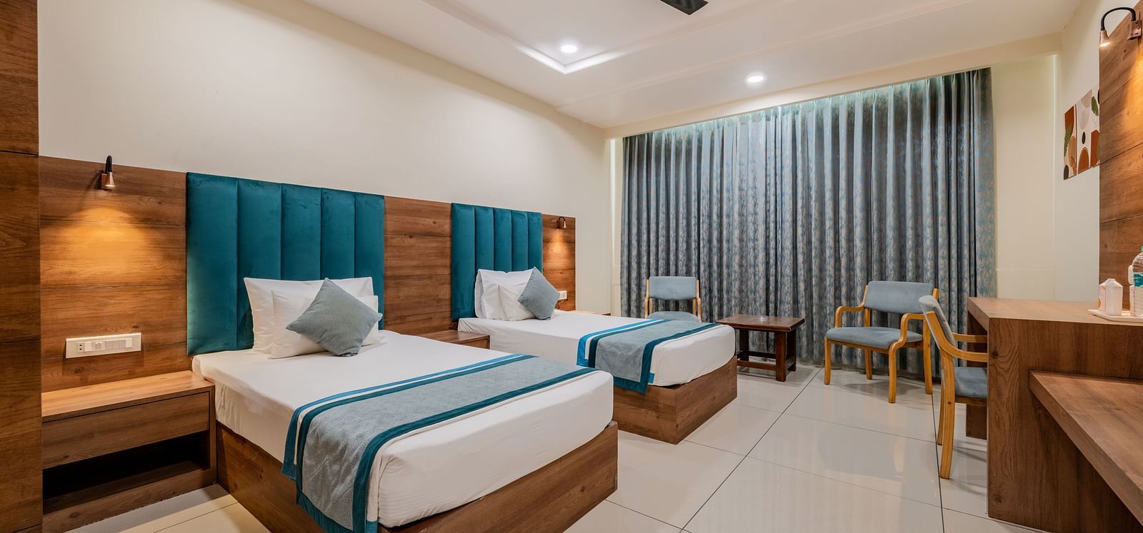 King Twin Bed Room with two single beds, teal headboards, and seating area at Hotel Highway King, Bilaspur.