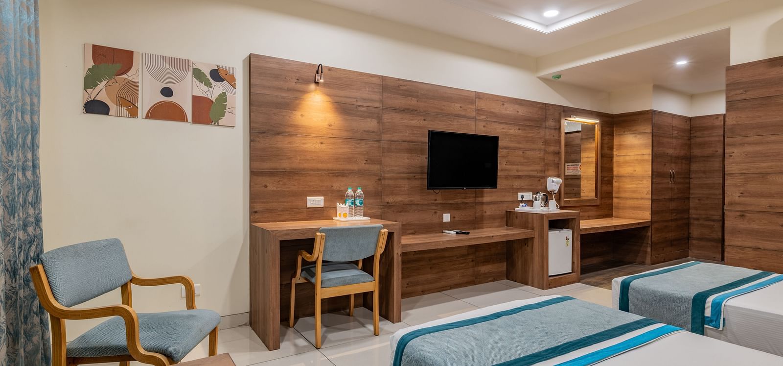 Warmly lit KIng Twin Bed Room with flat-screen TV, chairs, ceiling fan, and writing desk at Hotel Highway King, Bilaspur.