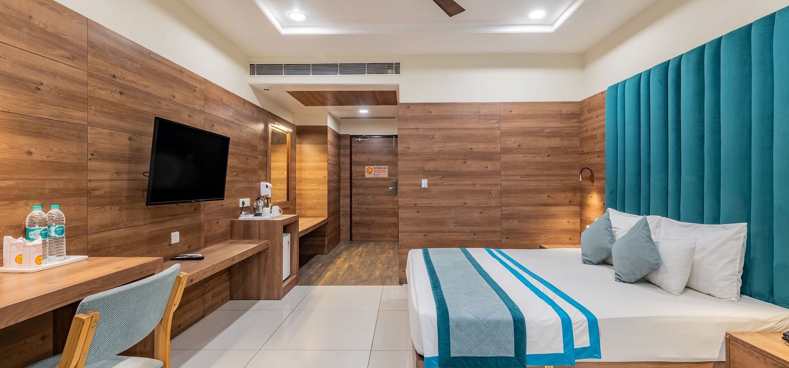 Spacious hotel room with a king size bed, wooden accents, ceiling fan, and work desk at Hotel Highway King, Bilaspur.