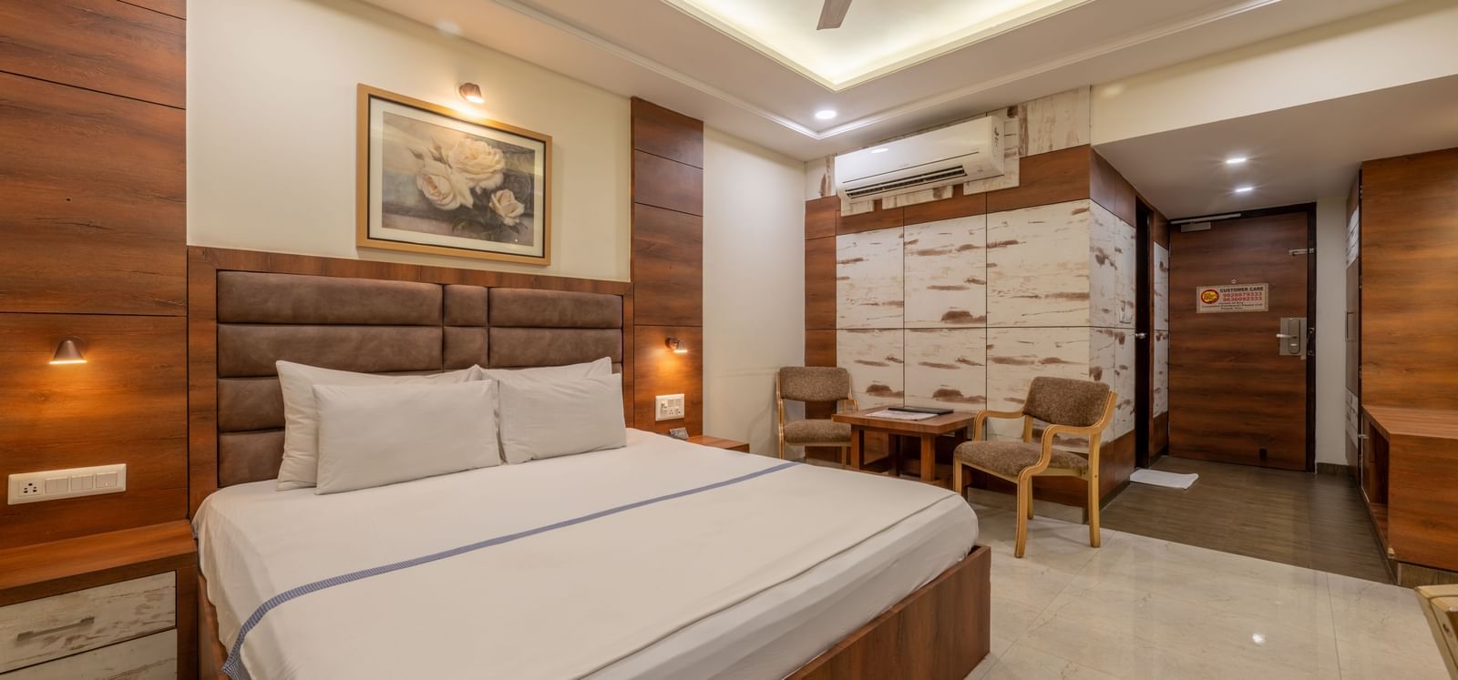 A bright room with a king size bed, a table with chairs and a wall art at Hotel Highway King, Jaipur.