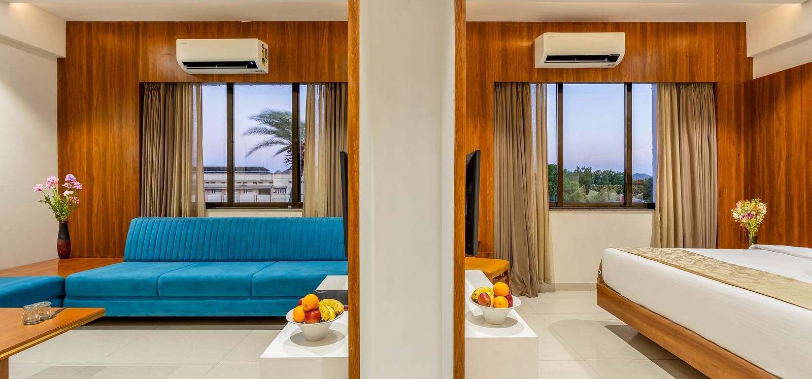 A spacious suite shows a living area with a sofa and a bedroom with a large bed, separated by a partition - Lords Eco Inn Ambaji.