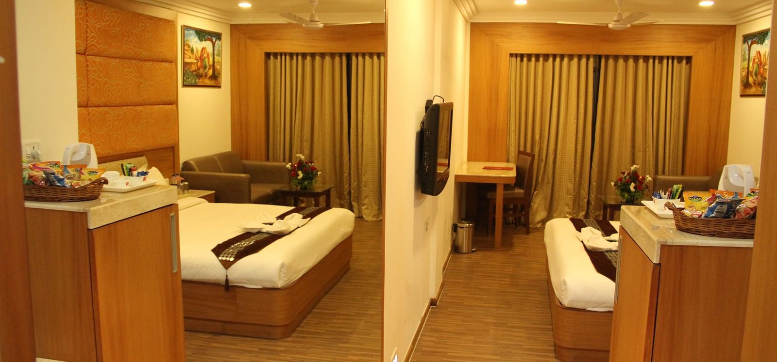 Spacious hotel room with sitting area and double bed, warmly lit