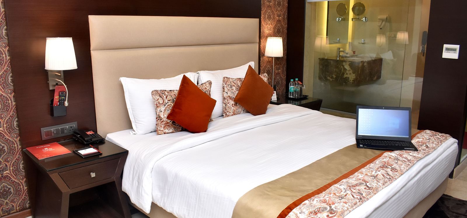 A guest room with a bed and a laptop on the side table at Lords Plaza Surat.