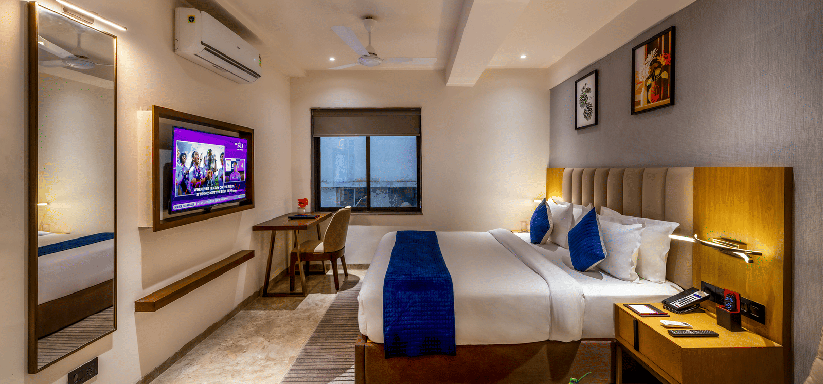 Modern interior with plush bedding, wall-mounted TV, and cozy ambience at Lords Studio Inn, Jamnagar.