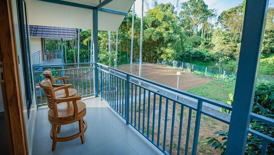 alt-text Balcony with two wooden seating chairs overlooking the property at Feel Free Retreat, Wayanad