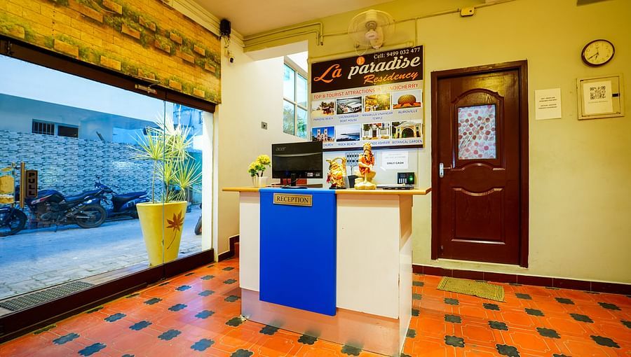 alt-text A front view of desk in the reception area with a glass door | La Paradise Residency, Pondicherry