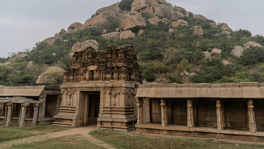 Historic stone temple entrance at the base of a large, boulder-covered hill.