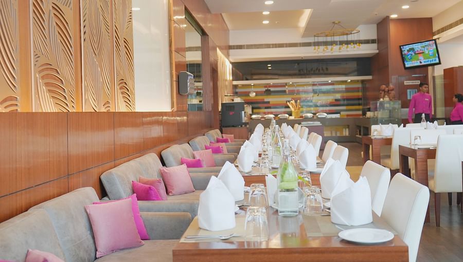 dining area at Nemesia with plush seating, elegant table settings, and a warm and inviting atmosphere. The space features a modern design with wood accents and decorative wall panels.