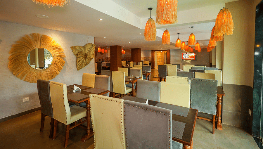 Interior of M Cafe with tables and chairs, and fancy lights hanging from the ceiling at Vagator Downtown, Goa