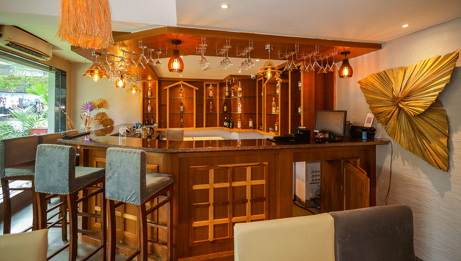 Cafe 24 with high seating chairs, wall decor, and wooden table counter at Vagator Downtown, Goa
