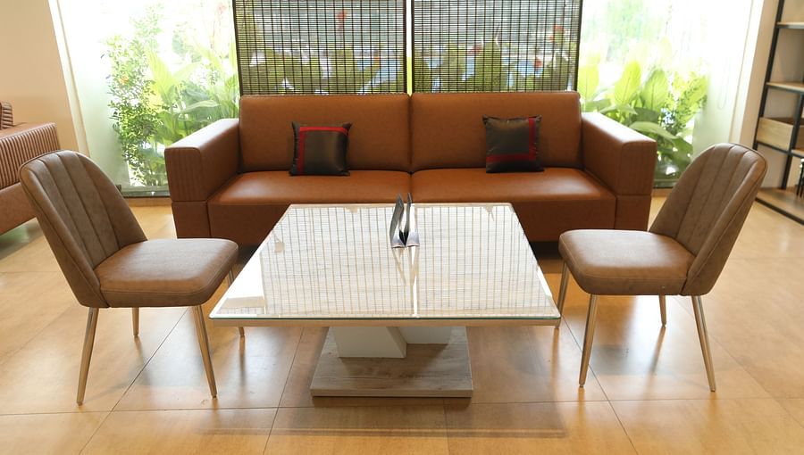 Brown chairs and couch arranged around a glass table
