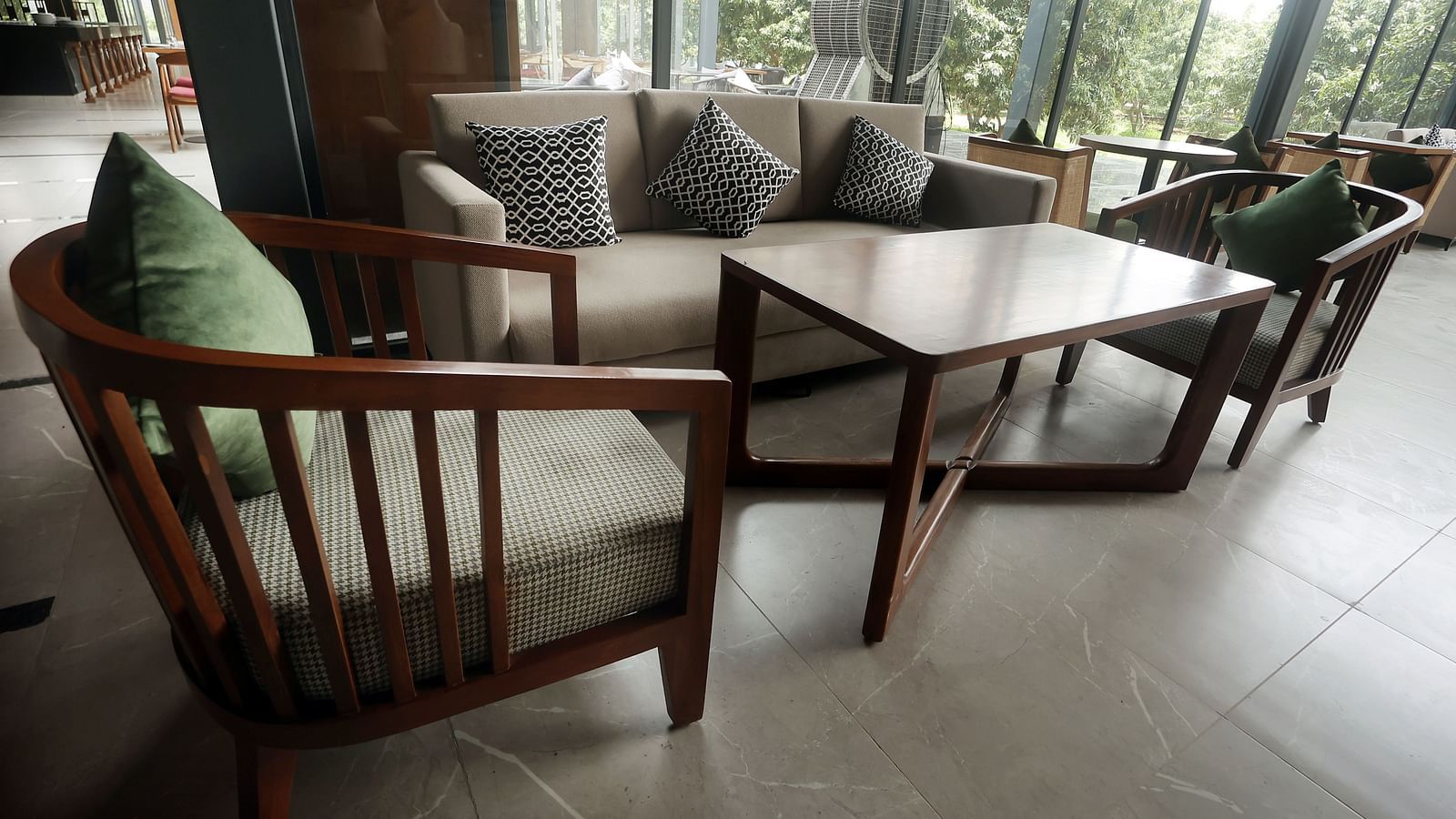 Bar area featuring a wooden sofa set with neutral-toned cushions near expansive windows at Wyndham Garden.