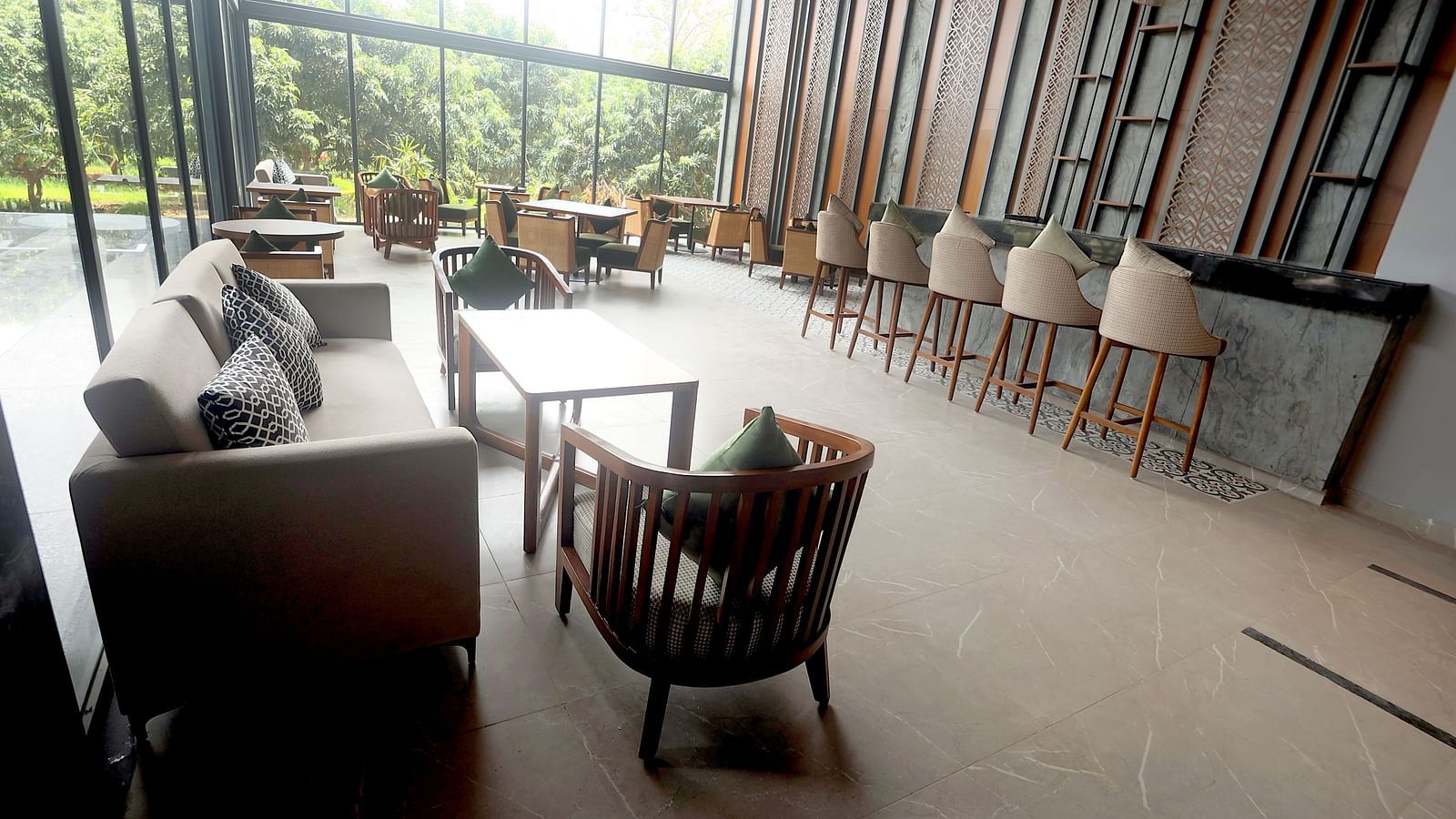 Stylish lounge and bar area with neutral-toned sofas and bar stools by large windows at Wyndham Garden.