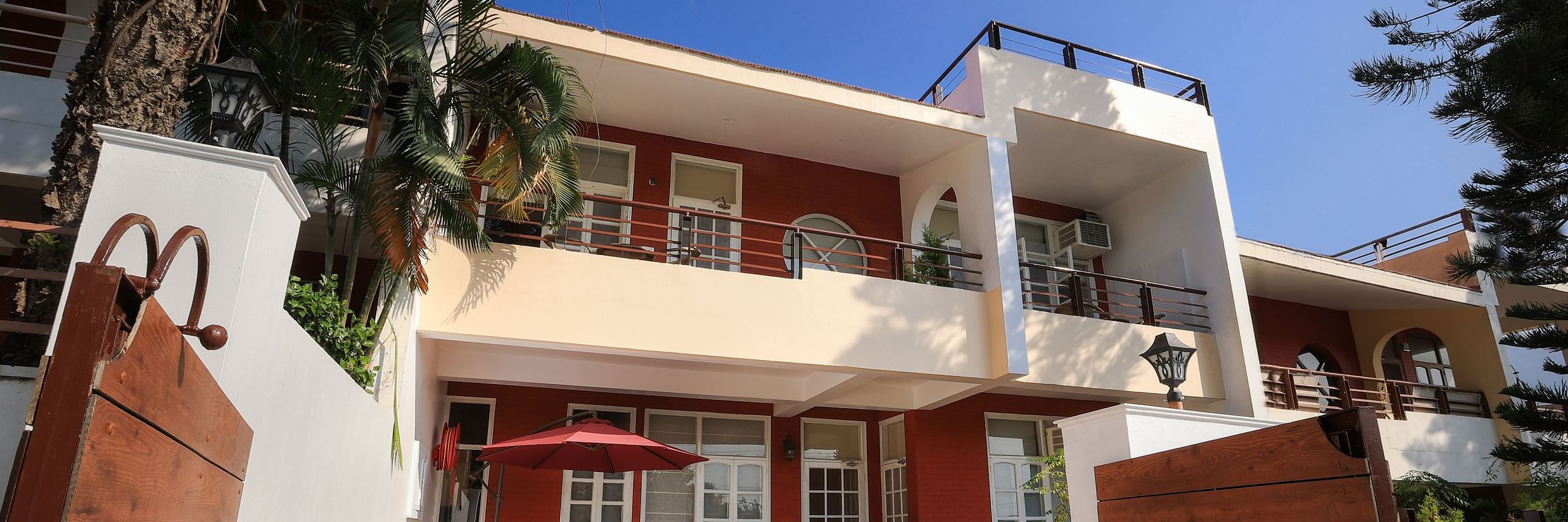 A facade image of a two storey building surrounded by trees and have a few flower pots beside the entrance pathway - Lamrin Boutique Cottages Rishikesh