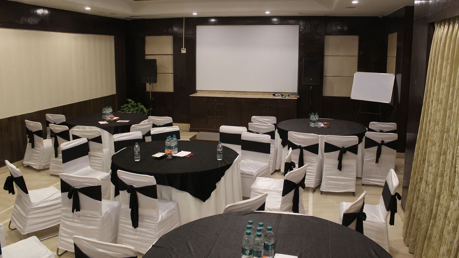 An image of a banquet hall  featuring a few round tables, each surrounded by chairs at Inde Hotel Signature Tower, Gurgaon