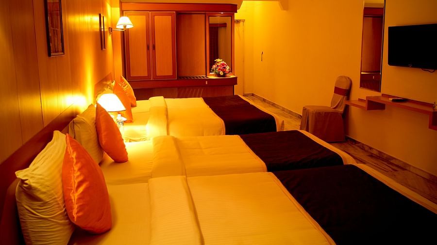  Hotel Yasodha Towers - Interior view of the suite rooms in Hosur featuring yellow lighting, beds lined up in a row and centralised air-conditioner