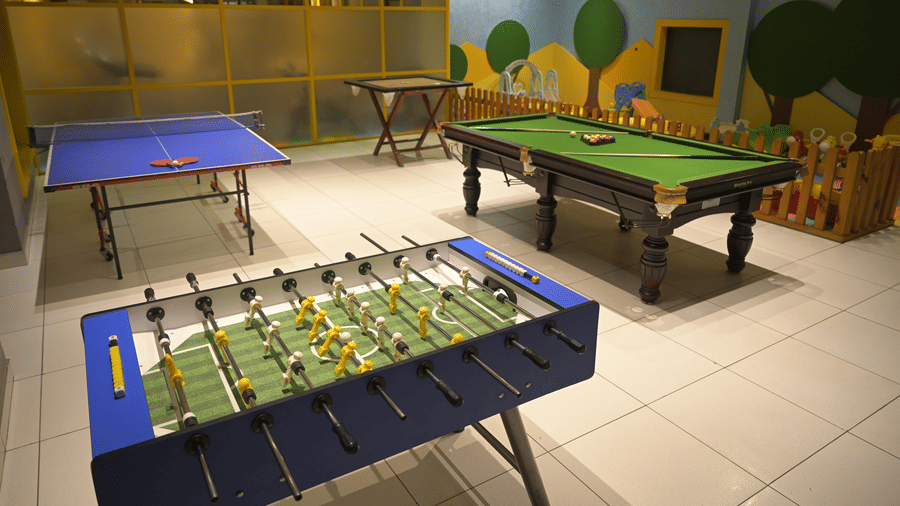 An indoor games room featuring a Foosball table, a pool table, and a table tennis setup at Hotel Sonar Bangla, Mayapur.