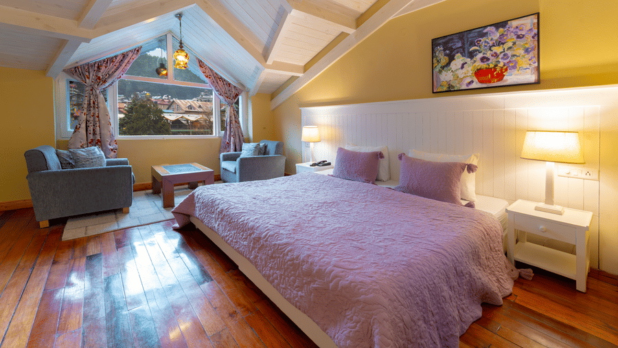 A cosy attic bedroom with a large window offering a view of the Manali mountains - Johnson Lodge & Spa, Manali