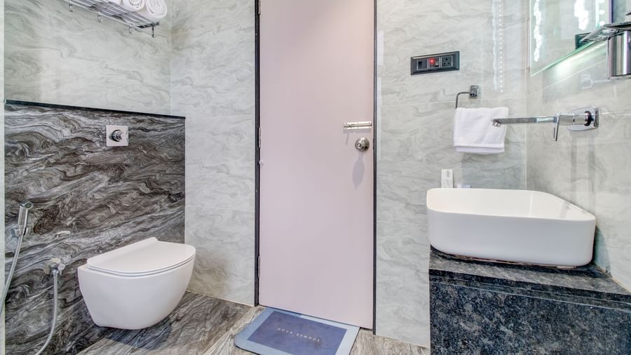 Contemporary bathroom with toilet, sink, and shower area at Monday Hotels Amalapuram Heights.