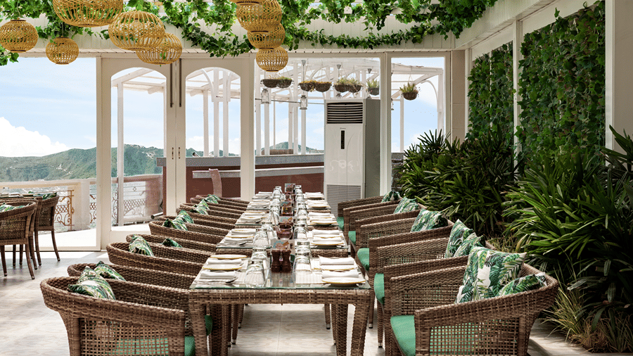 An indoor restaurant layout showing a long dining tables beneath hanging leafy decor at Ramada by Wyndham Mussoorie Mall Road.