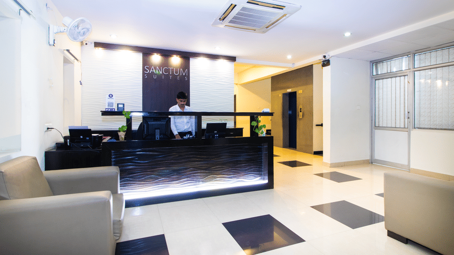 Hotel lobby with a reception desk, lounge seating, and a cassette air conditioner at Sanctum Suites Indiranagar, Bangalore.