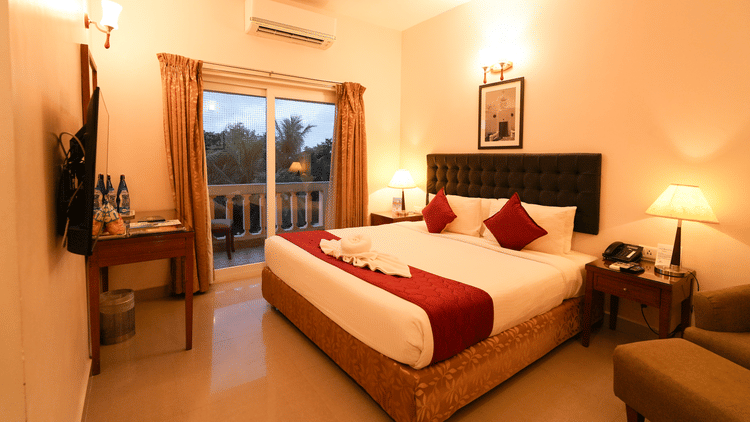 Image of Grandeur Pool View Suite featuring a plush bed facing the TV on the wall and the door to balcony next to the nightstand