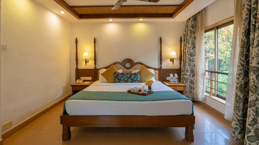 A room of Adamo The Bellus with vintage themed wooden bed with its unique architecture and the colour palate of the curtains which showcases the theme of the room..