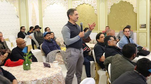 An image of a person speaking on a mic in a room full of people at Heritage Village Resorts & Spa