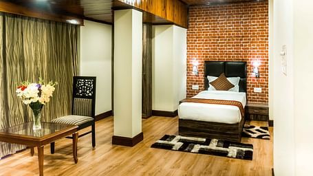 An image of a suite at the Ecotel Tin Tin, Bijanbari featuring a single bed, bed side tables, a table and a chair and other amenities