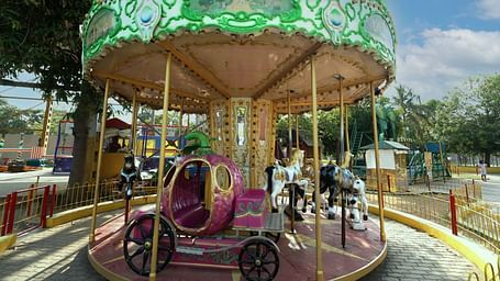 A Gracy Horse ride for kids featuring horses which has a small sit inside it's tummy. There are several such horses with seats which rotates under one umbrella at MGM Dizzee World.