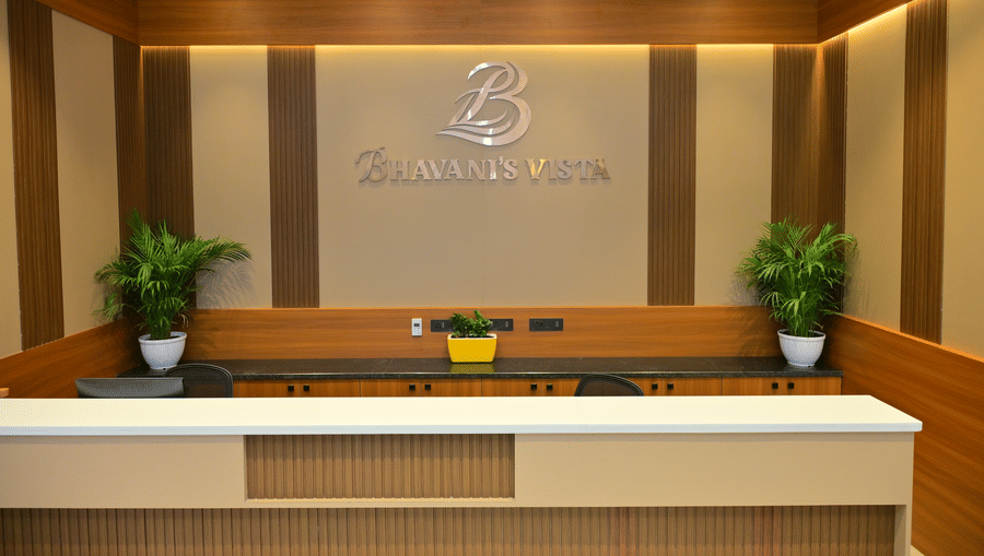 Reception desk of Bhavanis Vista By Icon featuring a counter, signage, and potted plants.